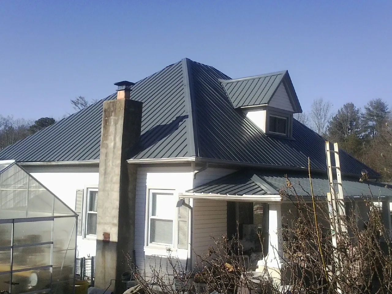 Dark blue standing seam metal roof on a white farmhouse with dormer — Slate & Tile Roof Repair by Roofing Brothers in Enon
