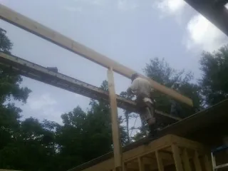 Carpenter setting a ridge beam over a new addition frame — Ice Dam Removal by Roofing Brothers in Enon