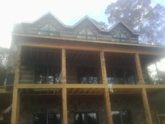 Dormers and porch framing on a large log home under construction — Roof Coating work by our crew in Enon