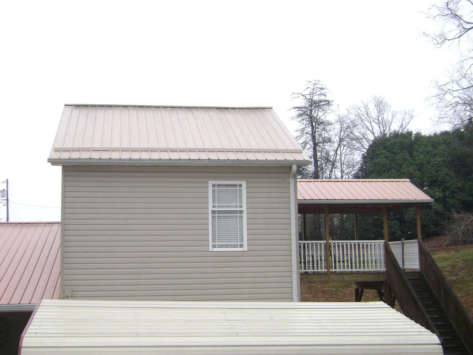 Tan metal roofs on a two story addition and attached porch, from a Roof Replacement job in Enon