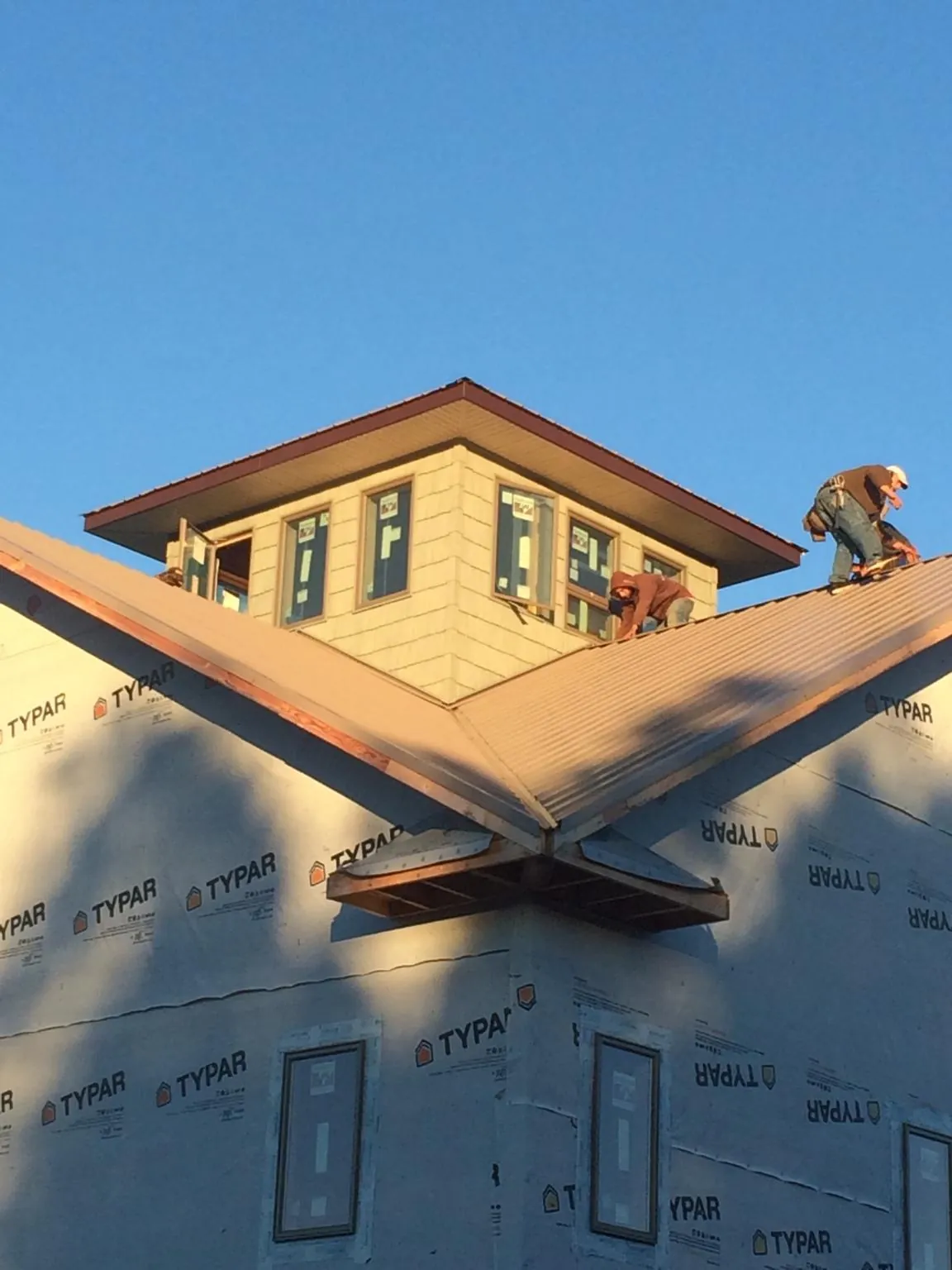 Roofers working around a rooftop cupola on a new metal roof at sunset — Roof Waterproofing in Enon by Roofing Brothers